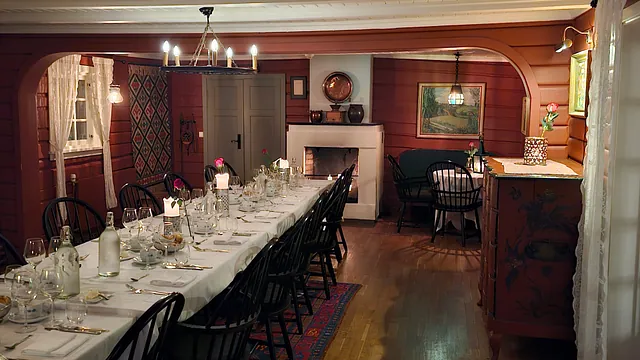 Spisestue med rød tømmervegger og svarte pinnestoler