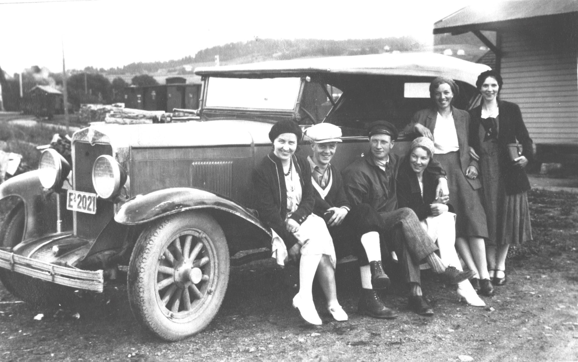 Old black and white photo with people standing next to an old Chevrolet