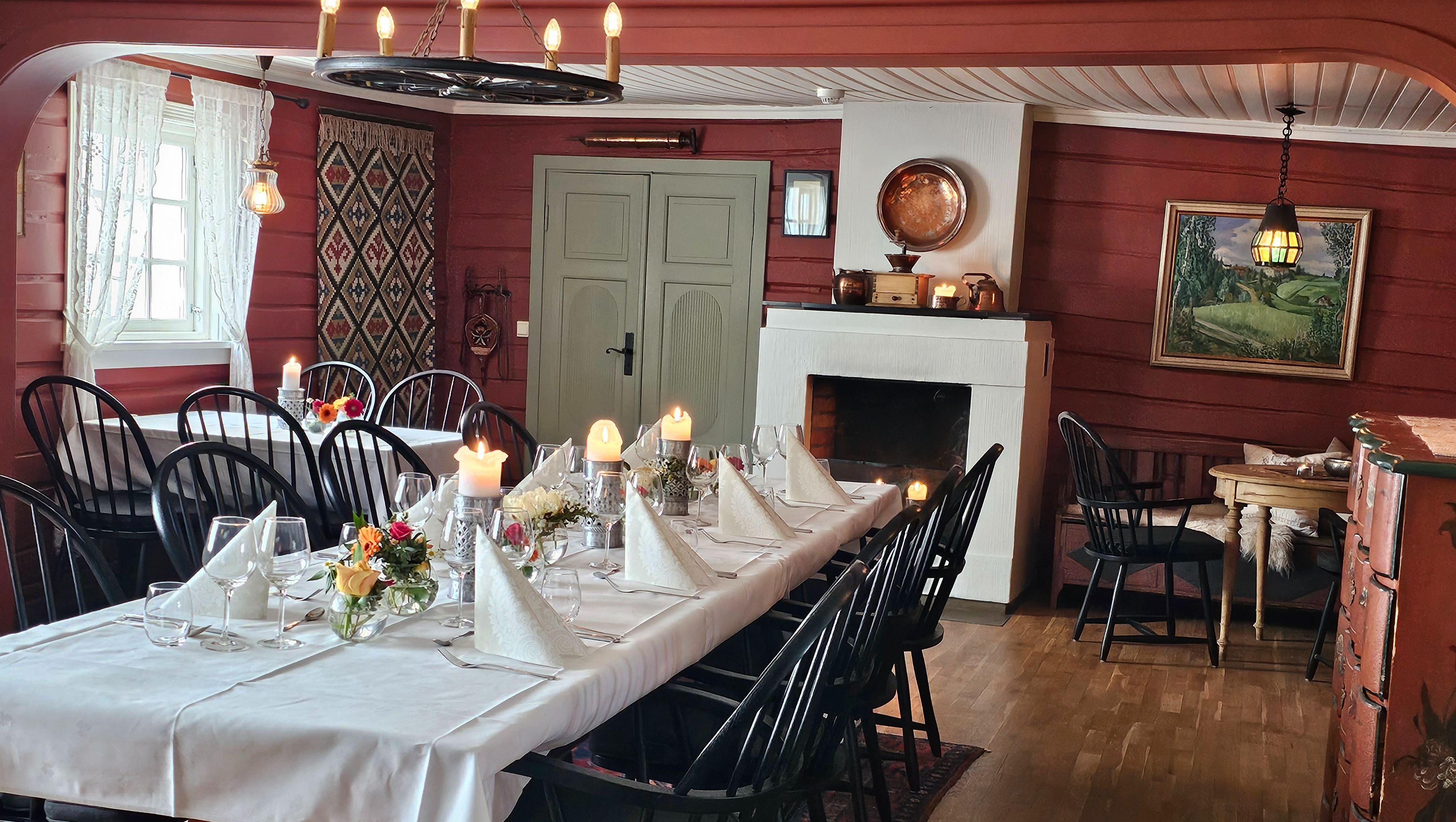 Spisestue med rød tømmervegger og svarte pinnestoler