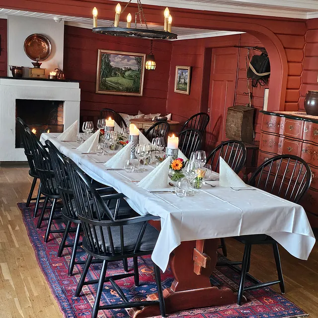 Spisestue med rød tømmervegger og svarte pinnestoler