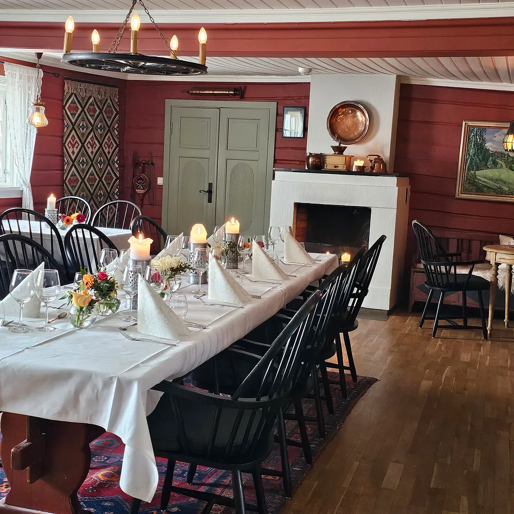 Spisestue med rød tømmervegger og svarte pinnestoler